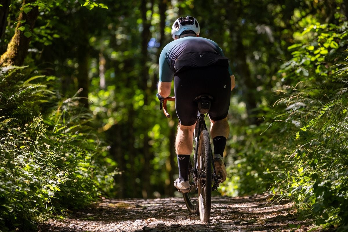 Cyclist riding bicycle on gravel road.