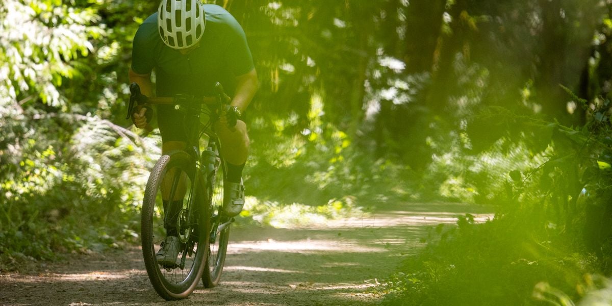 Cyclist riding bicycle on gravel road.