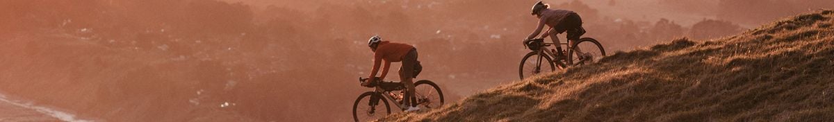 A pair of cyclists riding down a trail at sunset