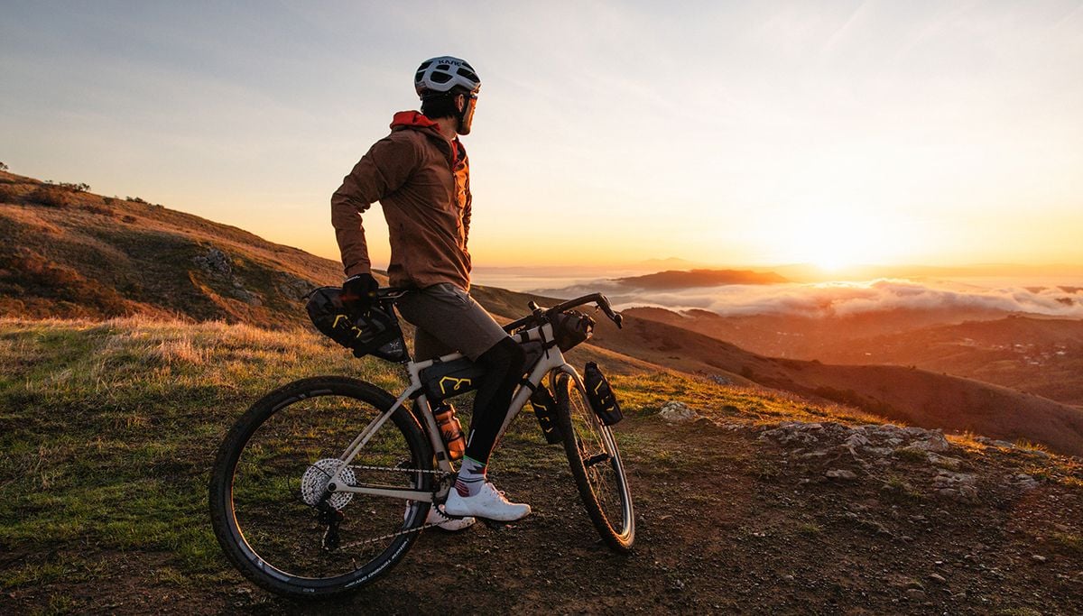 Cyclist looking across a valley toward sunset