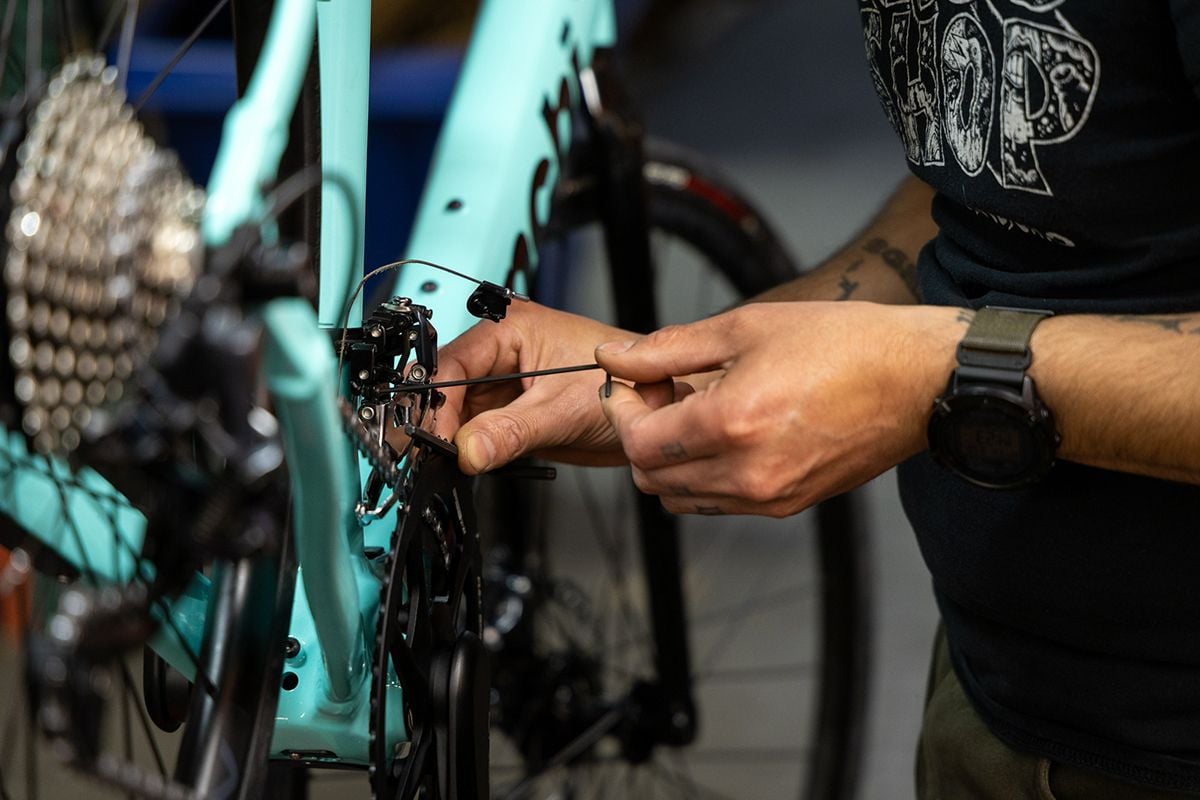 Bicycle mechanic working on front derailleur of bicycle