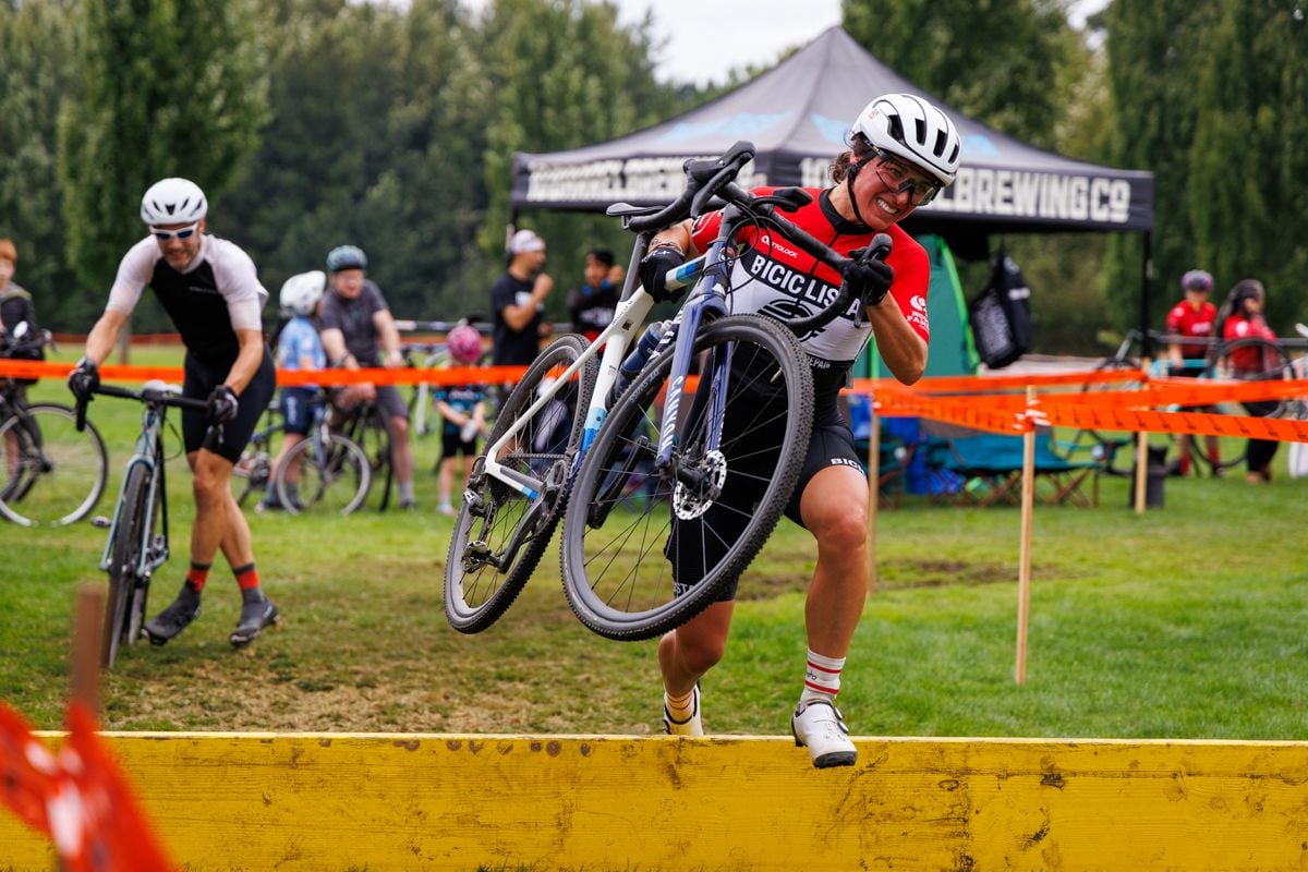 A rider jumping over a cyclocross barrier